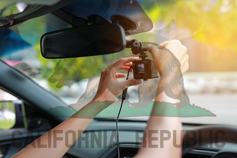 man adjusting dash cam in car